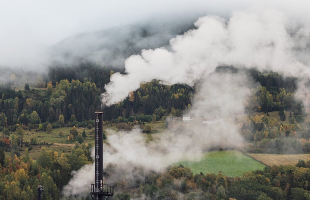 Industrial smokestack blowing smoke over a smoky landscape
