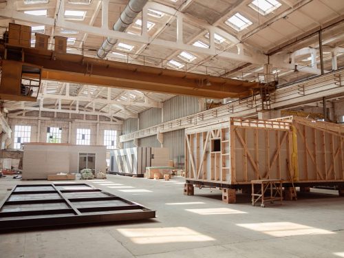 Building under construction with concrete floor, building materials, construction cabins and ceiling with windows