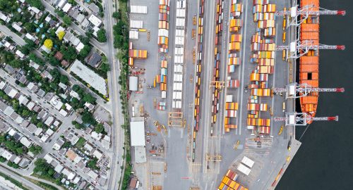 Aerial view of shipping containers and cranes at a port beside a residential neighbourhood